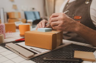 Küçük bir çevrimiçi işletme sahibi müşterilere göndermeden önce doğruluk için kutucukları işaretliyor, paket, bir çalışan müşterilere gönderilmek üzere ürünleri kutulara koyuyor