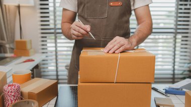 Paketleme odasındaki kutuları kontrol ediyor, küçük bir işletme sahibi kutuları müşterilere, ürünlere, e-ticarete, çevrimiçi satış ve ihracat şirketlerindeki girişimcilere göndermek için hazırlıyor.