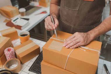 Paketleme odasındaki kutuları kontrol ediyor, küçük bir işletme sahibi kutuları müşterilere, ürünlere, e-ticarete, çevrimiçi satış ve ihracat şirketlerindeki girişimcilere göndermek için hazırlıyor.