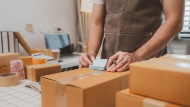 Çalışan, müşterilere nakliyeye hazırlanmak için ürünleri kutulara koyuyor, küçük bir online işletme sahibi müşterilere göndermeden önce doğruluk için kutucukları işaretliyor, paket,