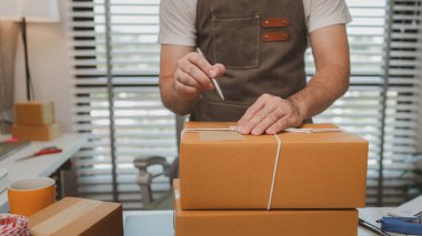 Paketleme odasındaki kutuları kontrol ediyor, küçük bir işletme sahibi kutuları müşterilere, ürünlere, e-ticarete, çevrimiçi satış ve ihracat şirketlerindeki girişimcilere göndermek için hazırlıyor.