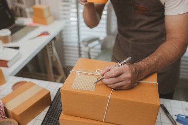 Paketleme odasındaki kutuları kontrol ediyor, küçük bir işletme sahibi kutuları müşterilere, ürünlere, e-ticarete, çevrimiçi satış ve ihracat şirketlerindeki girişimcilere göndermek için hazırlıyor.