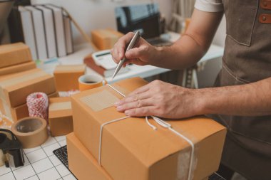 Paketleme odasındaki kutuları kontrol ediyor, küçük bir işletme sahibi kutuları müşterilere, ürünlere, e-ticarete, çevrimiçi satış ve ihracat şirketlerindeki girişimcilere göndermek için hazırlıyor.