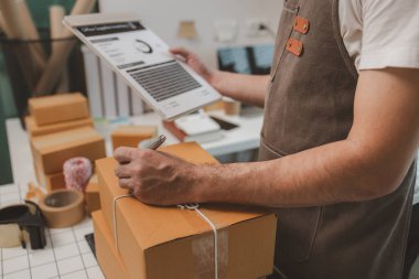 Paketleme odasındaki kutuları kontrol ediyor, küçük bir işletme sahibi kutuları müşterilere, ürünlere, e-ticarete, çevrimiçi satış ve ihracat şirketlerindeki girişimcilere göndermek için hazırlıyor.
