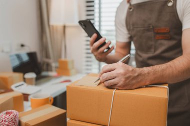 Paketleme odasındaki kutuları kontrol ediyor, küçük bir işletme sahibi kutuları müşterilere, ürünlere, e-ticarete, çevrimiçi satış ve ihracat şirketlerindeki girişimcilere göndermek için hazırlıyor.