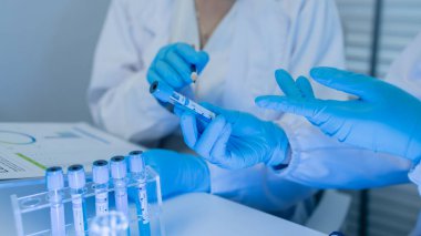 İki bilimadamı laboratuvarda sıvı madde üzerinde bir deney yaparken birbirlerine danışırlar, iki kimyager derleme, araştırma ve laboratuvar için deneysel veri alışverişinde bulunurlar.,