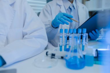 İki bilimadamı laboratuvarda sıvı madde üzerinde bir deney yaparken birbirlerine danışırlar, iki kimyager derleme, araştırma ve laboratuvar için deneysel veri alışverişinde bulunurlar.,