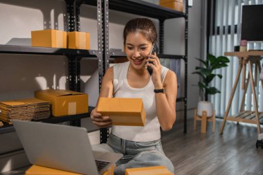 Paketleyici, bir müşteriye teslim edilmeden önce paketin durumunu kontrol eder, küçük bir işletme sahibi bir depodaki kutuları inceler, raflarla dolu bir depo ve paket