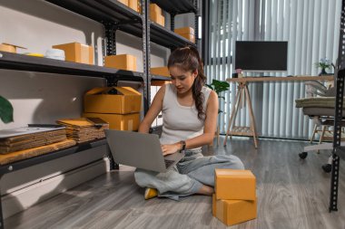 Bir bayan çalışan depodaki paket kutularını kontrol ediyor, bir depo müdürü raflardaki paket kutularını sayıyor, küçük bir online işletme sahibi bir depo odasında.