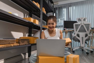 Bir bayan çalışan depodaki paket kutularını kontrol ediyor, bir depo müdürü raflardaki paket kutularını sayıyor, küçük bir online işletme sahibi bir depo odasında.