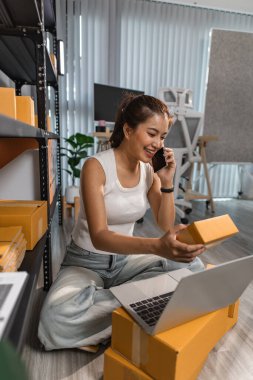 Depodaki paket kutularıyla çalışan bir çalışan depodaki paket kutularının sayısını kontrol eder. Nakliye işindeki bir girişimci depoyu teftiş etmek için gelir.