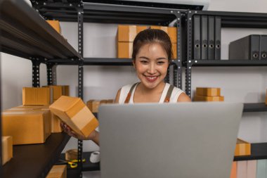 Depodaki paket kutularıyla çalışan bir çalışan depodaki paket kutularının sayısını kontrol eder. Nakliye işindeki bir girişimci depoyu teftiş etmek için gelir.