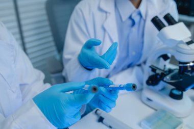 İki bilimadamı laboratuvarda sıvı madde üzerinde bir deney yaparken birbirlerine danışırlar, iki kimyager derleme, araştırma ve laboratuvar için deneysel veri alışverişinde bulunurlar.,