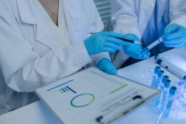 İki bilimadamı laboratuvarda sıvı madde üzerinde bir deney yaparken birbirlerine danışırlar, iki kimyager derleme, araştırma ve laboratuvar için deneysel veri alışverişinde bulunurlar.,