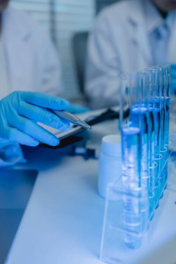 Bir kadın kimyager laboratuvarda çeşitli sıvı bileşiklerini test ediyor, bir bilim adamı bu gelişim üzerine araştırma yapıyor, laboratuvar, test tüpü ve bilimsel ekipmanlarda çalışırken önlük giyiyor.