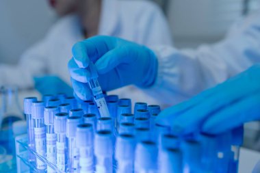 Bir kadın kimyager laboratuvarda çeşitli sıvı bileşiklerini test ediyor, bir bilim adamı bu gelişim üzerine araştırma yapıyor, laboratuvar, test tüpü ve bilimsel ekipmanlarda çalışırken önlük giyiyor.