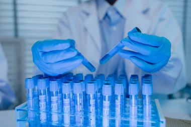 Bir kadın kimyager laboratuvarda çeşitli sıvı bileşiklerini test ediyor, bir bilim adamı bu gelişim üzerine araştırma yapıyor, laboratuvar, test tüpü ve bilimsel ekipmanlarda çalışırken önlük giyiyor.