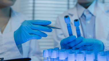 İki bilimadamı laboratuvarda sıvı madde üzerinde bir deney yaparken birbirlerine danışırlar, iki kimyager derleme, araştırma ve laboratuvar için deneysel veri alışverişinde bulunurlar.,