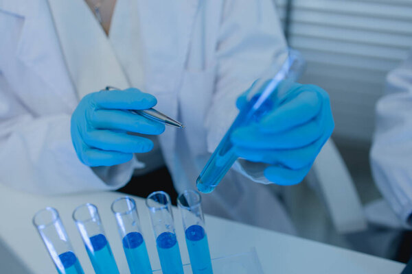 a female chemist is testing various liquid compounds in a lab, a scientist is doing research on the development, she wears a lab coat when she works in laboratory, test tube, scientific equipment