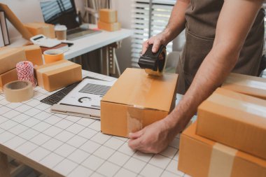 Küçük bir çevrimiçi işletme sahibi müşterilere göndermeden önce doğruluk için kutucukları işaretliyor, paket, bir çalışan müşterilere gönderilmek üzere ürünleri kutulara koyuyor