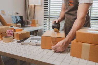 Çalışan, müşterilere nakliyeye hazırlanmak için ürünleri kutulara koyuyor, küçük bir online işletme sahibi müşterilere göndermeden önce doğruluk için kutucukları işaretliyor, paket,