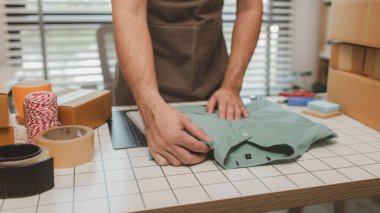 Küçük bir çevrimiçi işletme sahibi müşterilere göndermeden önce doğruluk için kutucukları işaretliyor, paket, bir çalışan müşterilere gönderilmek üzere ürünleri kutulara koyuyor