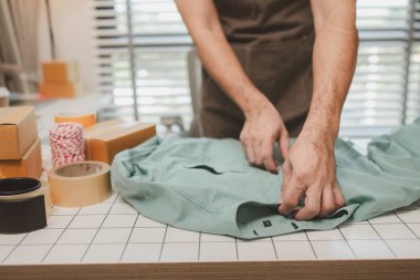 Küçük bir çevrimiçi işletme sahibi müşterilere göndermeden önce doğruluk için kutucukları işaretliyor, paket, bir çalışan müşterilere gönderilmek üzere ürünleri kutulara koyuyor