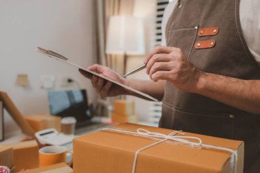 Çalışan, müşterilere nakliyeye hazırlanmak için ürünleri kutulara koyuyor, küçük bir online işletme sahibi müşterilere göndermeden önce doğruluk için kutucukları işaretliyor, paket,