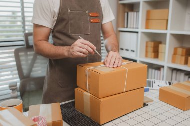 Paketleme odasındaki kutuları kontrol ediyor, küçük bir işletme sahibi kutuları müşterilere, ürünlere, e-ticarete, çevrimiçi satış ve ihracat şirketlerindeki girişimcilere göndermek için hazırlıyor.