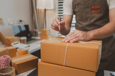 Paketleme odasındaki kutuları kontrol ediyor, küçük bir işletme sahibi kutuları müşterilere, ürünlere, e-ticarete, çevrimiçi satış ve ihracat şirketlerindeki girişimcilere göndermek için hazırlıyor.