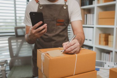 Paketleme odasındaki kutuları kontrol ediyor, küçük bir işletme sahibi kutuları müşterilere, ürünlere, e-ticarete, çevrimiçi satış ve ihracat şirketlerindeki girişimcilere göndermek için hazırlıyor.