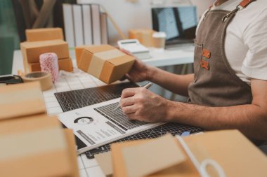 Paketleme odasındaki kutuları kontrol ediyor, küçük bir işletme sahibi kutuları müşterilere, ürünlere, e-ticarete, çevrimiçi satış ve ihracat şirketlerindeki girişimcilere göndermek için hazırlıyor.