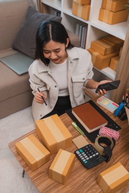 Girişimci müşteri siparişi için paket topluyor. Küçük bir işletmesi var. Sme, odada bir sürü paket var.