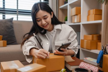 Girişimci müşteri siparişi için paket topluyor. Küçük bir işletmesi var. Sme, odada bir sürü paket var.