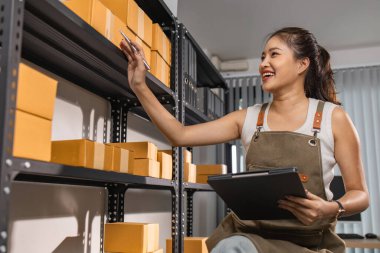 Depo çalışanı depoda paketlenmiş kutuları işaretliyor. Çevrimiçi iş yapan küçük bir işletme sahibi müşterilere, paketlere, e-ticarete göndermek için paket paketliyor.,