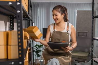 Depo çalışanı depoda paketlenmiş kutuları işaretliyor. Çevrimiçi iş yapan küçük bir işletme sahibi müşterilere, paketlere, e-ticarete göndermek için paket paketliyor.,