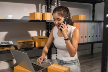 Paketleyici, bir müşteriye teslim edilmeden önce paketin durumunu kontrol eder, küçük bir işletme sahibi bir depodaki kutuları inceler, raflarla dolu bir depo ve paket