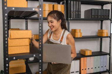 Paketleyici, bir müşteriye teslim edilmeden önce paketin durumunu kontrol eder, küçük bir işletme sahibi bir depodaki kutuları inceler, raflarla dolu bir depo ve paket