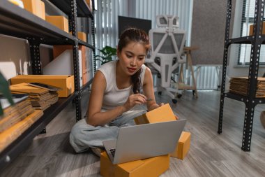 Bir bayan çalışan depodaki paket kutularını kontrol ediyor, bir depo müdürü raflardaki paket kutularını sayıyor, küçük bir online işletme sahibi bir depo odasında.