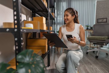 Bir bayan çalışan depodaki paket kutularını kontrol ediyor, bir depo müdürü raflardaki paket kutularını sayıyor, küçük bir online işletme sahibi bir depo odasında.