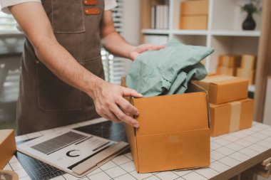 Küçük bir çevrimiçi işletme sahibi müşterilere göndermeden önce doğruluk için kutucukları işaretliyor, paket, bir çalışan müşterilere gönderilmek üzere ürünleri kutulara koyuyor