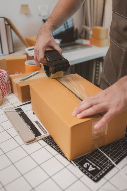 Çalışan, müşterilere nakliyeye hazırlanmak için ürünleri kutulara koyuyor, küçük bir online işletme sahibi müşterilere göndermeden önce doğruluk için kutucukları işaretliyor, paket,