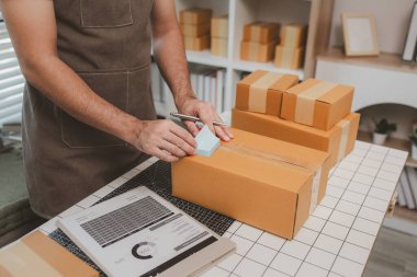 Çalışan, müşterilere nakliyeye hazırlanmak için ürünleri kutulara koyuyor, küçük bir online işletme sahibi müşterilere göndermeden önce doğruluk için kutucukları işaretliyor, paket,