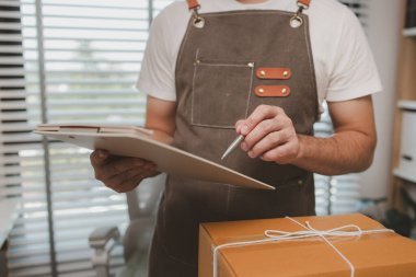 Çalışan, müşterilere nakliyeye hazırlanmak için ürünleri kutulara koyuyor, küçük bir online işletme sahibi müşterilere göndermeden önce doğruluk için kutucukları işaretliyor, paket,