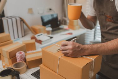 Paketleme odasındaki kutuları kontrol ediyor, küçük bir işletme sahibi kutuları müşterilere, ürünlere, e-ticarete, çevrimiçi satış ve ihracat şirketlerindeki girişimcilere göndermek için hazırlıyor.