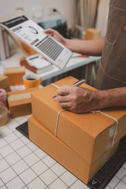 Paketleme odasındaki kutuları kontrol ediyor, küçük bir işletme sahibi kutuları müşterilere, ürünlere, e-ticarete, çevrimiçi satış ve ihracat şirketlerindeki girişimcilere göndermek için hazırlıyor.