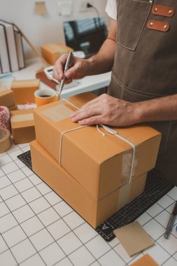 Paketleme odasındaki kutuları kontrol ediyor, küçük bir işletme sahibi kutuları müşterilere, ürünlere, e-ticarete, çevrimiçi satış ve ihracat şirketlerindeki girişimcilere göndermek için hazırlıyor.
