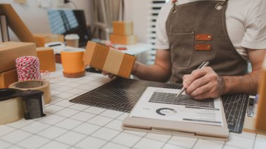 Paketleme odasındaki kutuları kontrol ediyor, küçük bir işletme sahibi kutuları müşterilere, ürünlere, e-ticarete, çevrimiçi satış ve ihracat şirketlerindeki girişimcilere göndermek için hazırlıyor.