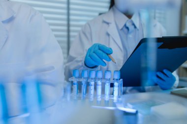 İki bilimadamı laboratuvarda sıvı madde üzerinde bir deney yaparken birbirlerine danışırlar, iki kimyager derleme, araştırma ve laboratuvar için deneysel veri alışverişinde bulunurlar.,