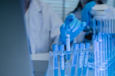 İki bilimadamı laboratuvarda sıvı madde üzerinde bir deney yaparken birbirlerine danışırlar, iki kimyager derleme, araştırma ve laboratuvar için deneysel veri alışverişinde bulunurlar.,